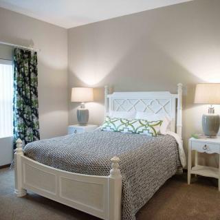 A cozy bedroom with a white bed, patterned bedding, and two lamps on nightstands.