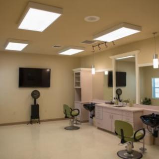 An empty hair salon interior with styling stations, chairs, and bright lighting.
