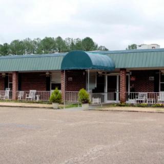 A building with a green awning and a parking lot in front.