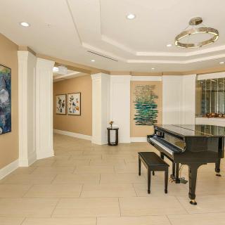 A modern hallway featuring a grand piano and various artworks on the walls.