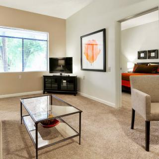 A modern living room with a coffee table, television, and artwork on the wall.
