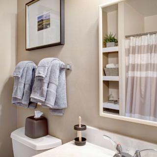 A modern bathroom with neatly arranged towels and a decorative wall art.