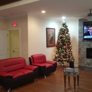 A cozy living room with red couches and a decorated Christmas tree next to a TV.