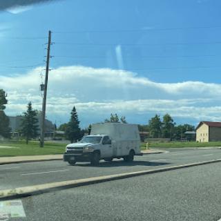 A white van parked on the roadside under a clear blue sky.