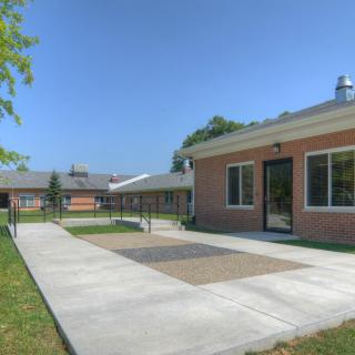 A sunny day view of a school building with a brick exterior and a pathway leading to the entrance.
