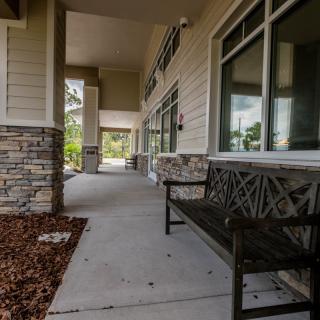 A modern building entrance with stone accents and a bench along the walkway.