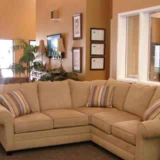 A cozy living room featuring a beige corner sofa with striped cushions.