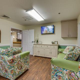 A cozy waiting room with colorful furniture and a television mounted on the wall.