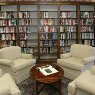 A cozy library reading area with armchairs and fully stocked bookshelves.