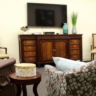 A cozy living room with a television mounted above a wooden cabinet and comfortable seating.
