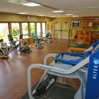 A spacious gym featuring a variety of exercise and rehabilitation equipment.