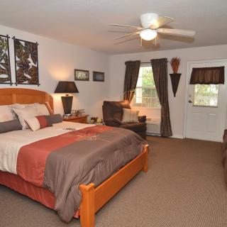 A cozy bedroom with a wooden bed, ceiling fan, and elegant decor.