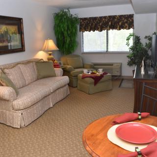 A cozy living room with a sofa, armchair, and neatly set table.