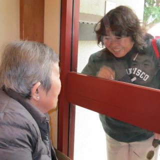 Two people interacting through a window, one indoors and the other outdoors.