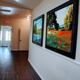 A hallway featuring vibrant landscape paintings on the wall, creating an inviting atmosphere.