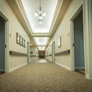 A well-lit hallway with doors on either side and carpeted flooring.