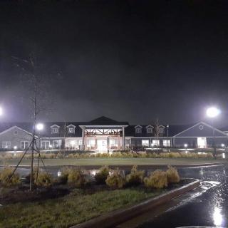 A well-lit building captured at night with reflections on the wet ground.