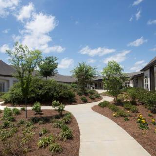 A sunny day in a landscaped residential courtyard with winding pathways and lush greenery.