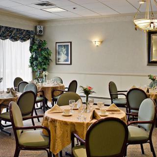A well-decorated dining room with round tables and upholstered chairs, set for a meal.