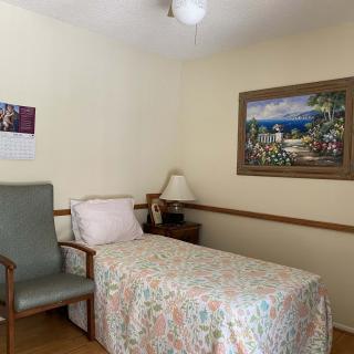 A cozy bedroom with a single bed, chair, and decorative elements.
