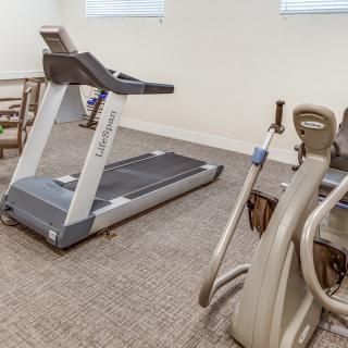 A small exercise room featuring a treadmill and other fitness equipment.