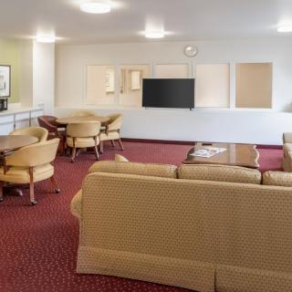 A spacious living area with sofas, chairs, and a television.