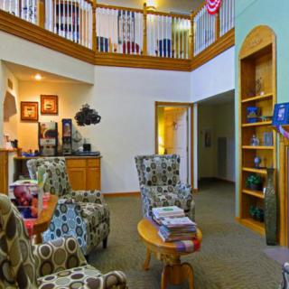 A cozy living room with patterned armchairs, a wooden coffee table, and a bookshelf set in a multilevel home.