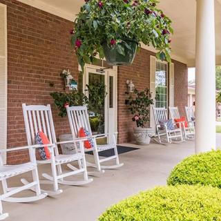 A cozy porch with white rocking chairs and hanging plants, perfect for relaxation.