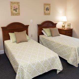 A cozy bedroom with two twin beds, decorative pillows, and matching wall art.