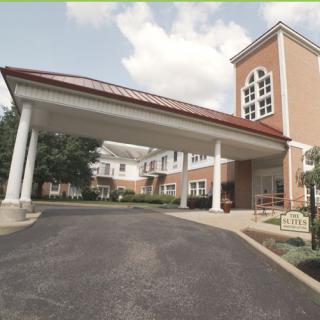An entrance to a building featuring a covered walkway supported by columns and a brick exterior.