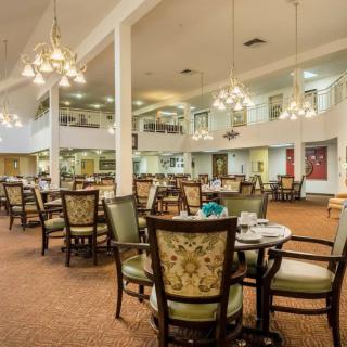 A spacious dining area with elegant chandeliers, set with multiple tables and chairs.