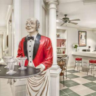 A statue of a waiter in a red jacket holding a tray, set in a stylish kitchen bar area.