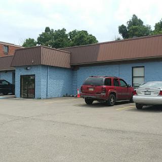 A commercial building with a blue exterior and parked vehicles in the lot.