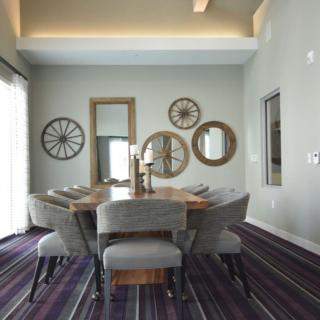 A modern dining room with a wooden table, upholstered chairs, and decorative wall mirrors.