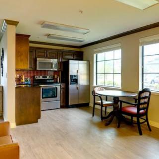 A cozy kitchen and dining area featuring modern appliances, a table with chairs, and large windows.