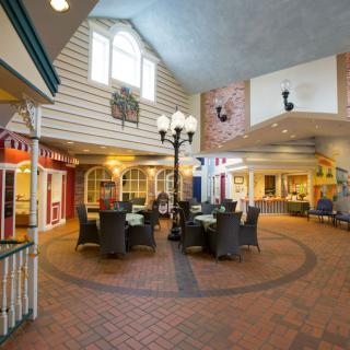 A cozy indoor dining area with wicker seating and a lamppost, featuring charming architecture and a brick floor.