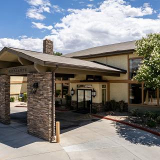 A hotel entrance with a stone-covered portico under a partly cloudy sky.