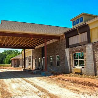 A photo of an unfinished building with a large entrance structure under clear blue skies.