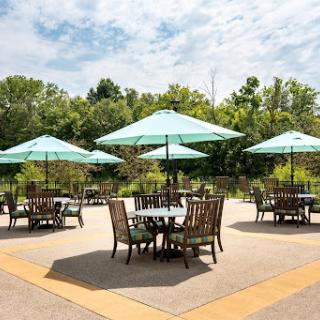A beautifully arranged outdoor seating area featuring tables with teal umbrellas surrounded by lush greenery.