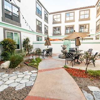 A cozy courtyard with outdoor seating and umbrellas, surrounded by an apartment building.
