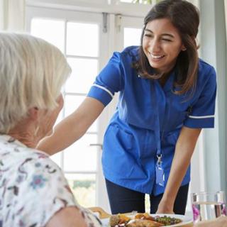 A nurse provides care and interacts with an elderly person at home.