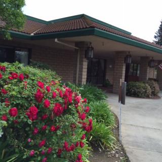 A building entrance surrounded by vibrant flowers and lush landscaping.