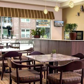 A cozy cafe interior with tables, chairs, and a view of the outside through large windows.