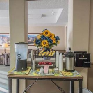 A breakfast setup featuring a coffee station, water dispenser, and pastries, decorated with vibrant sunflowers.