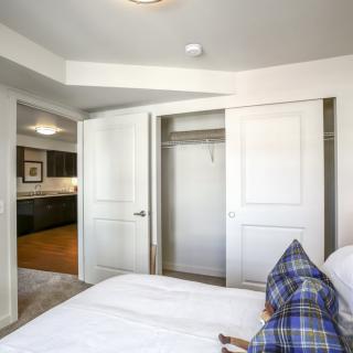 A bedroom with an open closet door, featuring a bed and pillows.