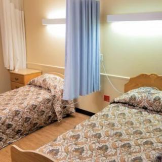 A simple hospital room with two beds separated by a curtain.