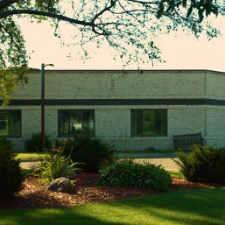 A serene view of a modest building surrounded by well-maintained greenery.
