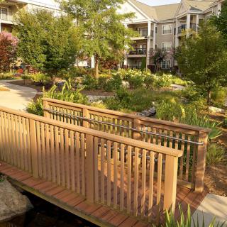 A charming wooden bridge spans across a lush garden in a residential complex.