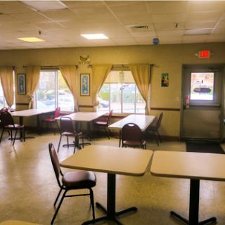 A spacious dining area with empty tables and soft natural light streaming in from the windows.