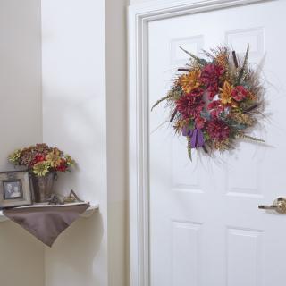 A door adorned with an autumn-themed wreath, featuring a vibrant floral arrangement in a cozy home interior.